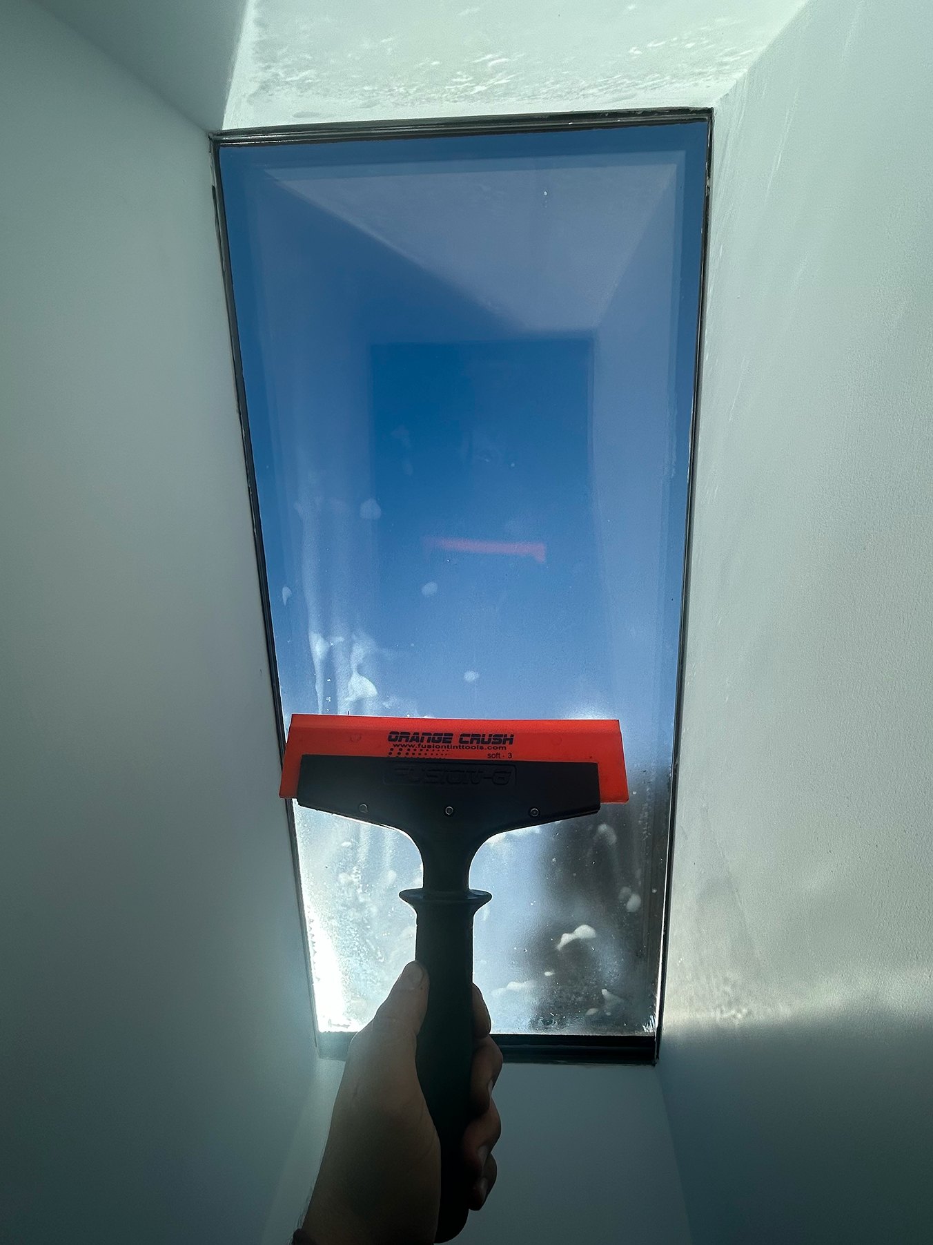 Residential window film being installed with a squeegee